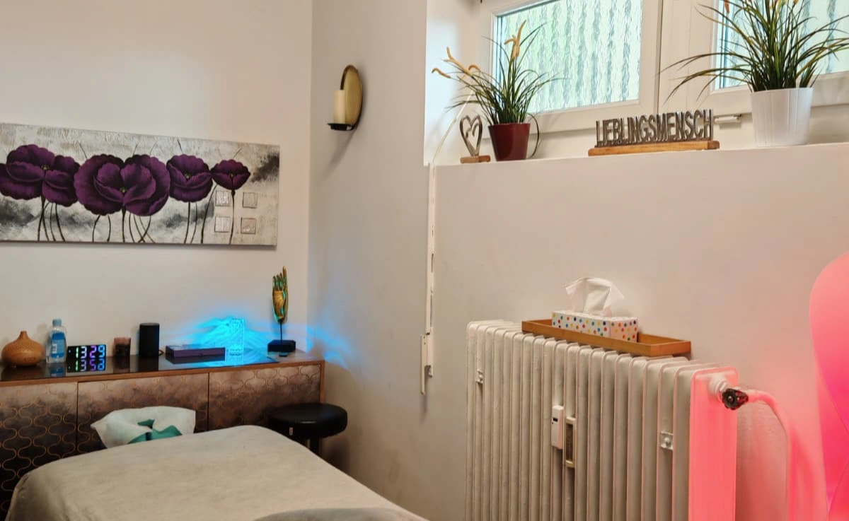 Massageraum Men2Men Schöneberg mit Behandlungsliege, Blumenkunst, LED-Beleuchtung und entspannender Atmosphäre