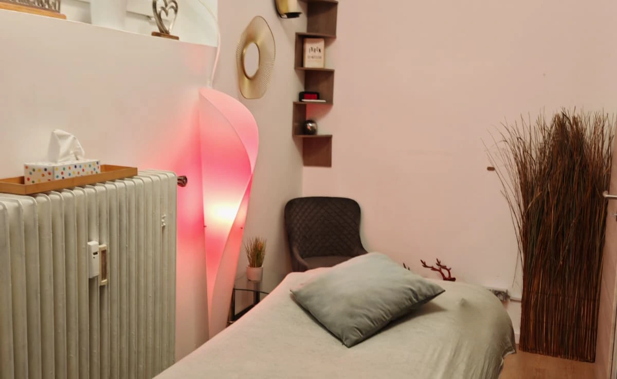 Massageraum Men2Men Schöneberg mit rosa Stimmungslicht, Liege und stilvollen Dekorationen